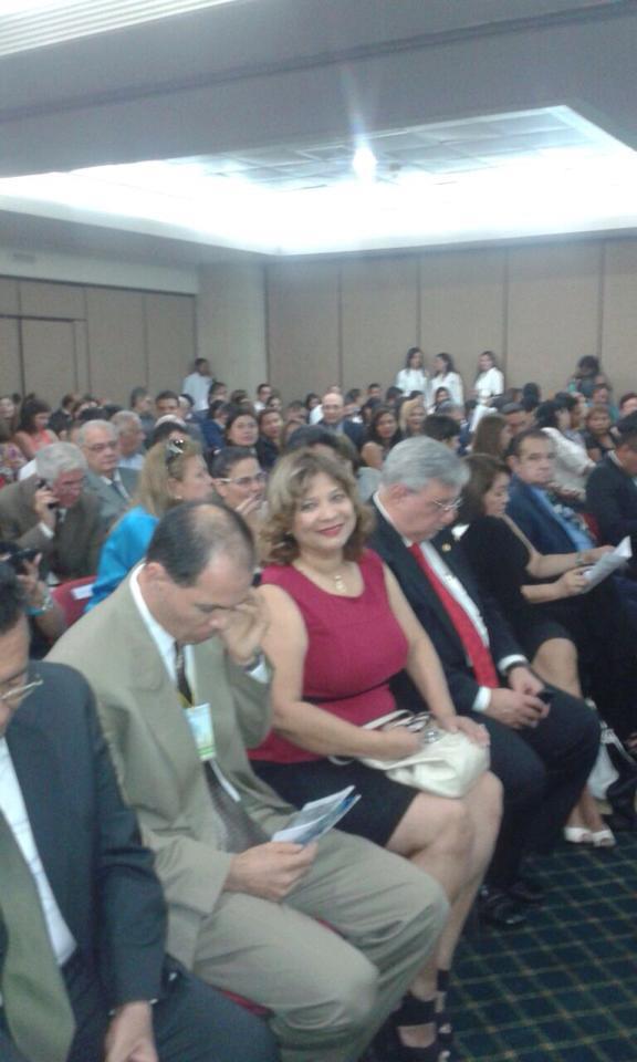María Zavala sentada entre el público de un congreso, sonriendo hacia la cámara