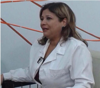 María Zavala con bata blanca, en una conversación profesional
